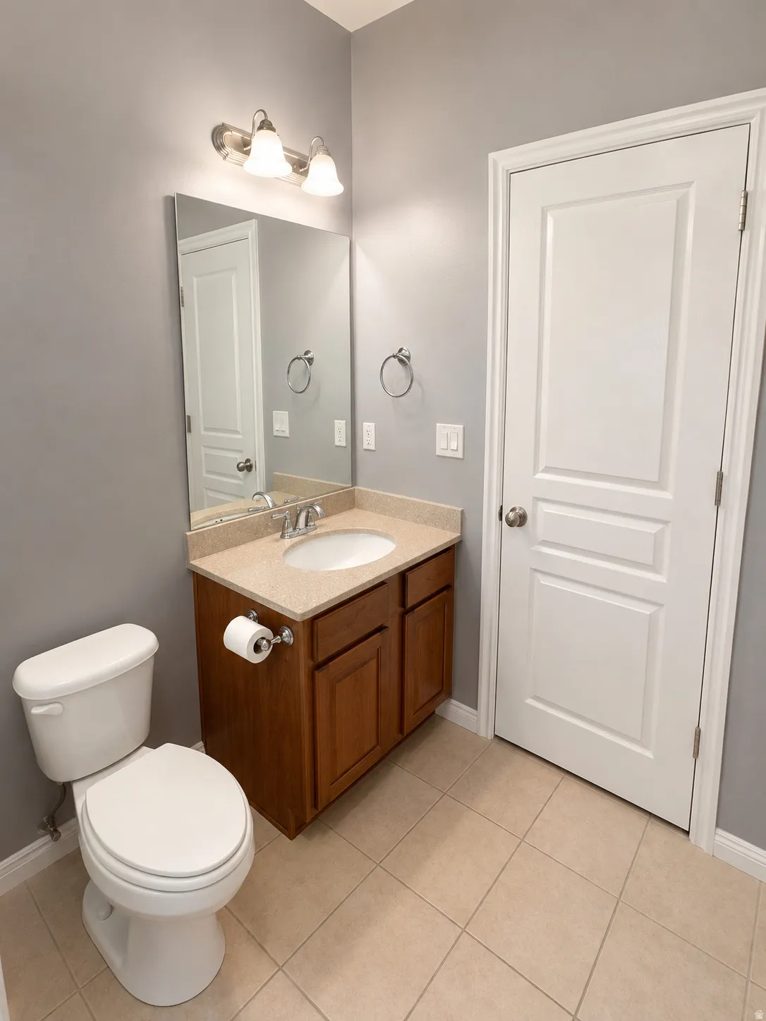 Bathroom featuring a wood-finish vanity with a light-colored countertop and undermount sink
