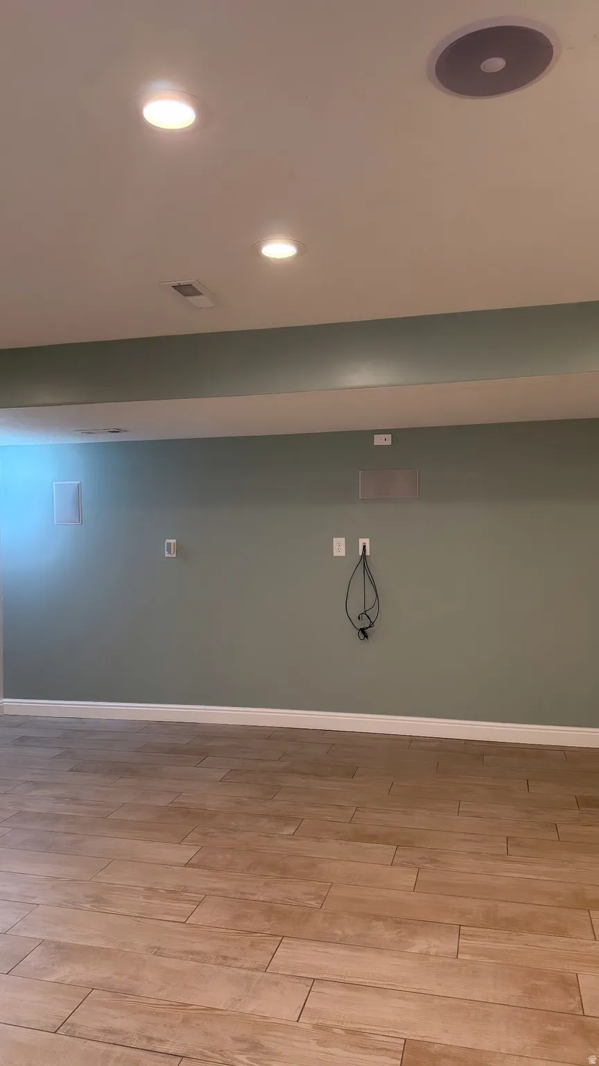 Recessed lighting illuminates the space, featuring wood-finish flooring and a built-in ceiling speaker
