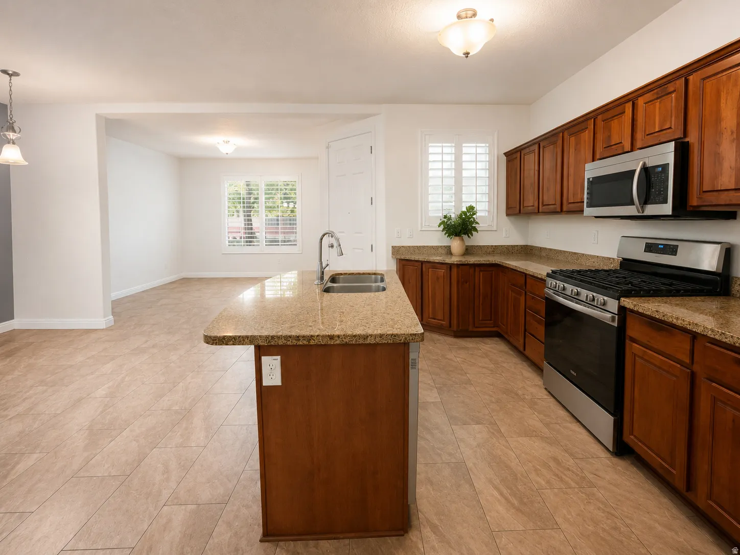 Kitchen featuring granite-style countertops, wood cabinetry, stainless steel appliances, and tile flooring