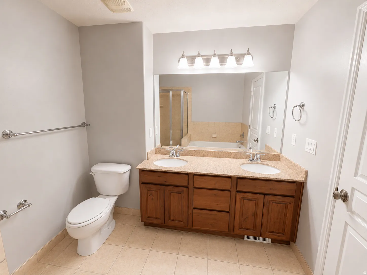 Bathroom featuring a dual vanity with a light-toned countertop and wood-finish cabinetry