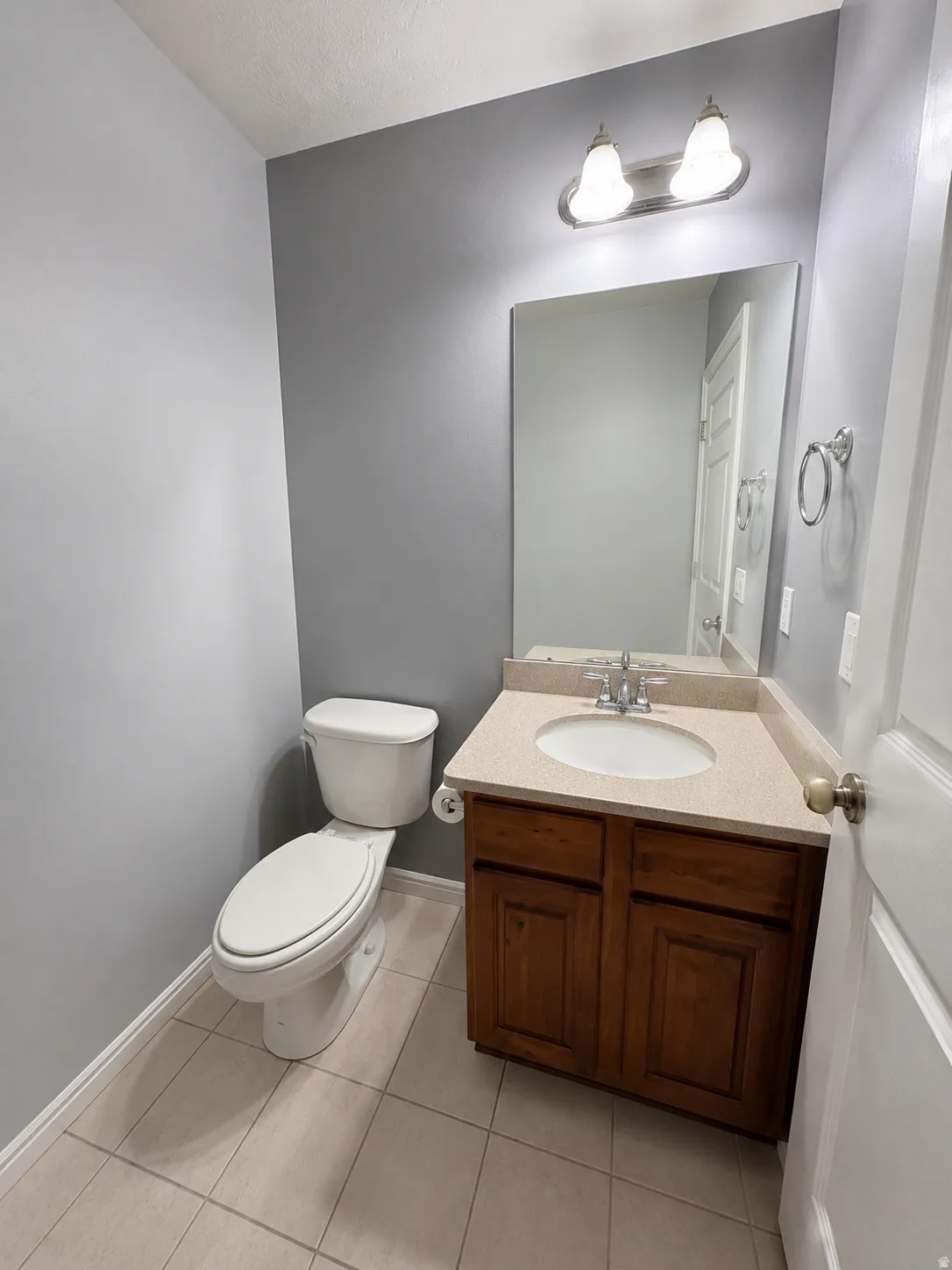 Bathroom featuring a vanity with a light-colored countertop, an integrated sink, and a wood-finish cabinet