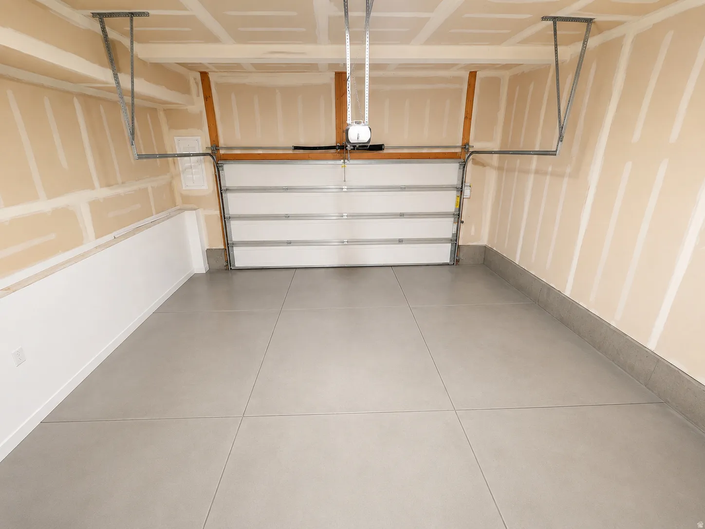 Spacious garage featuring a concrete floor, overhead door, and ceiling-mounted garage door opener