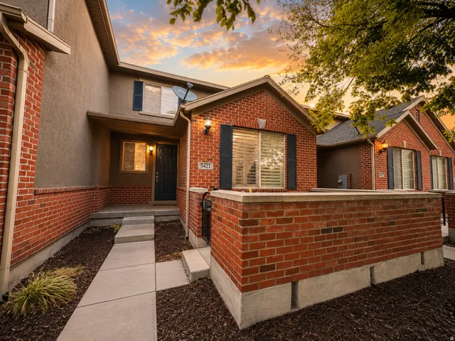Brick and stucco exterior featuring black shutters and an entry porch light