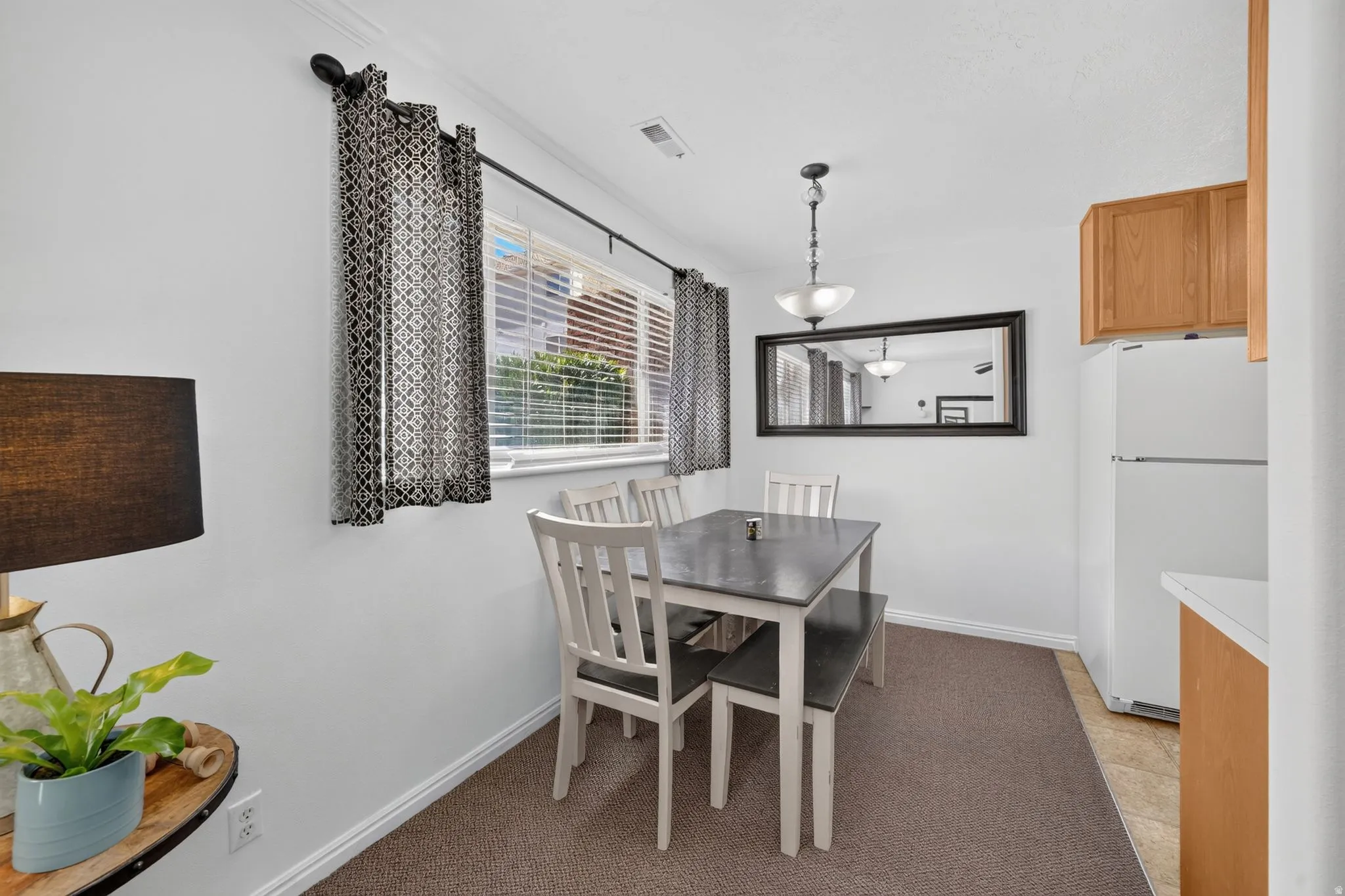 Dining area featuring a window with blinds, carpeted flooring, and a ceiling-mounted light fixture