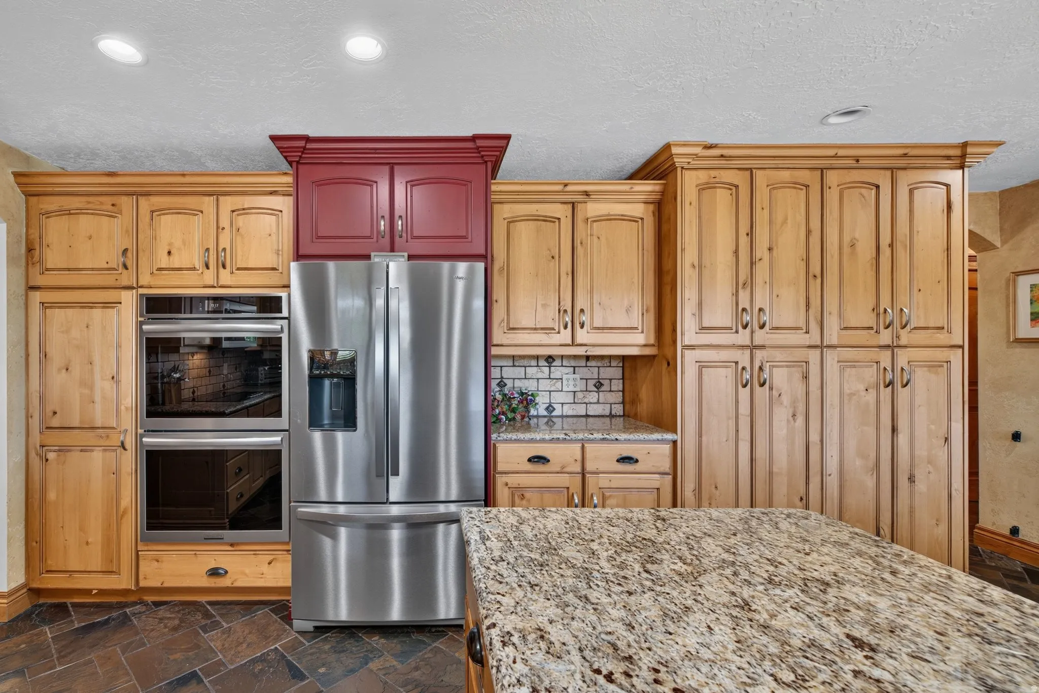 Kitchen featuring stainless steel French door refrigerator, double wall ovens, and an expansive island with a granite countertop