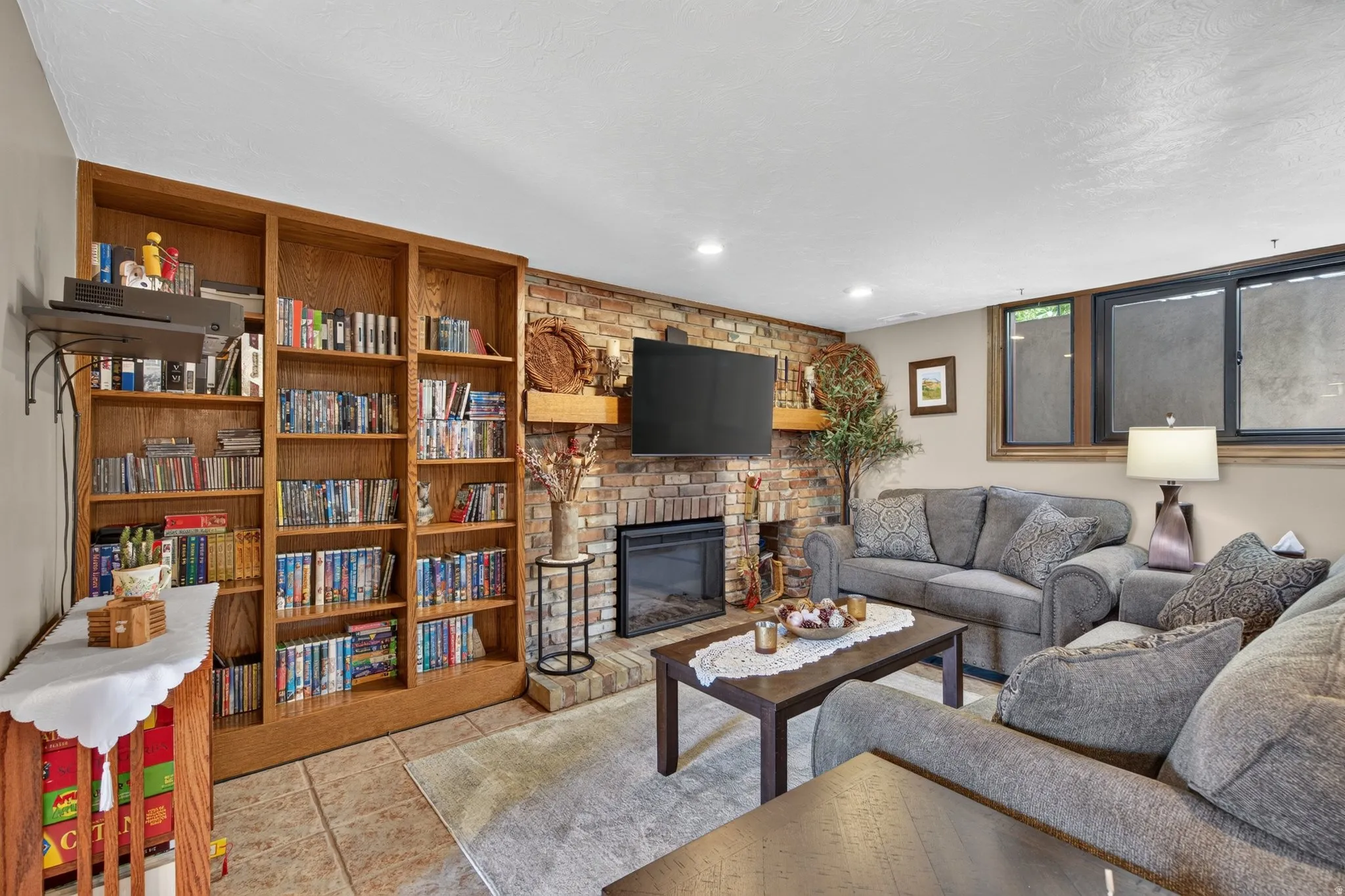 Living area featuring a brick-faced fireplace with hearth, a wood mantel, and built-in shelving