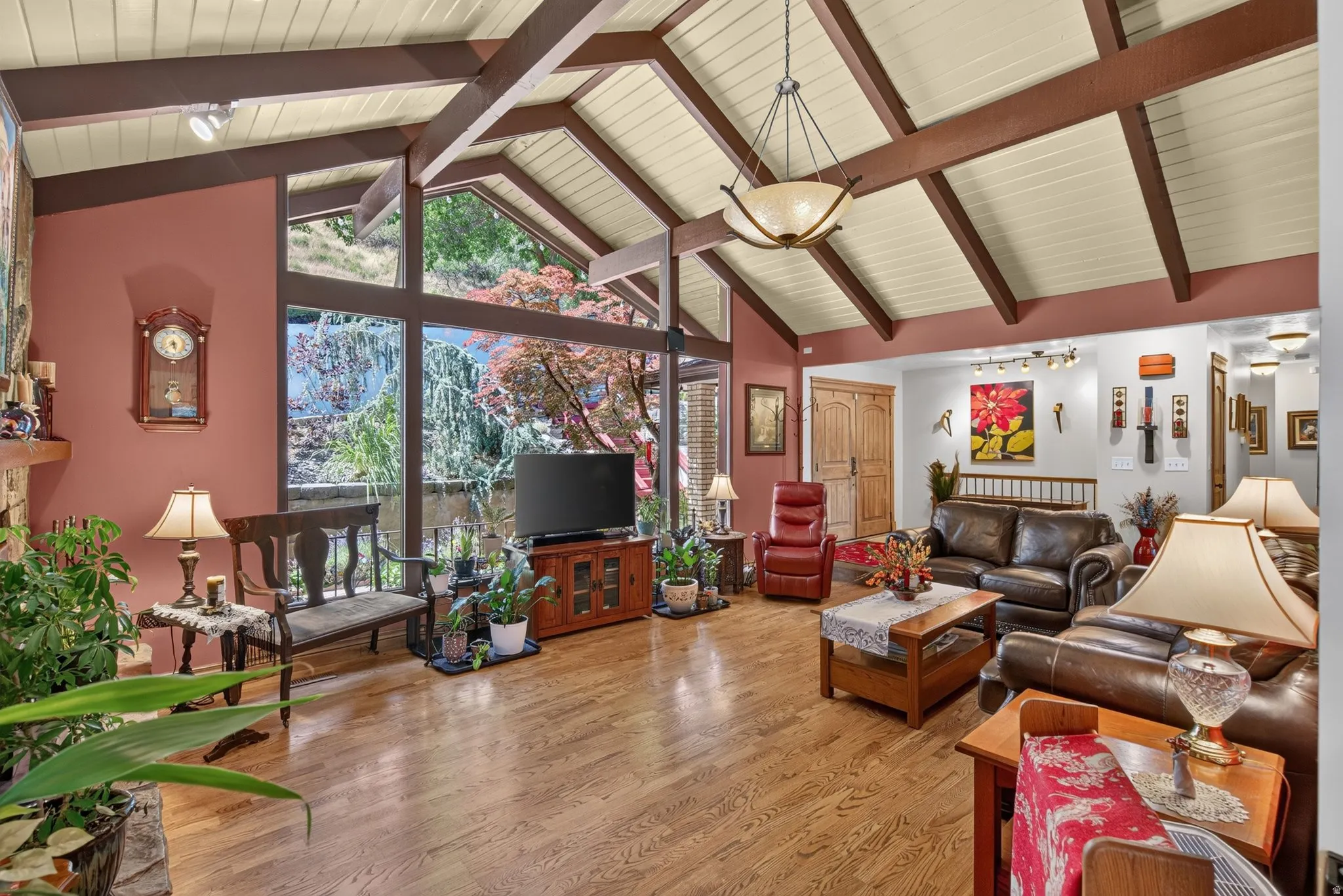 Vaulted ceiling with exposed beams, wood-finish flooring, and a large window wall