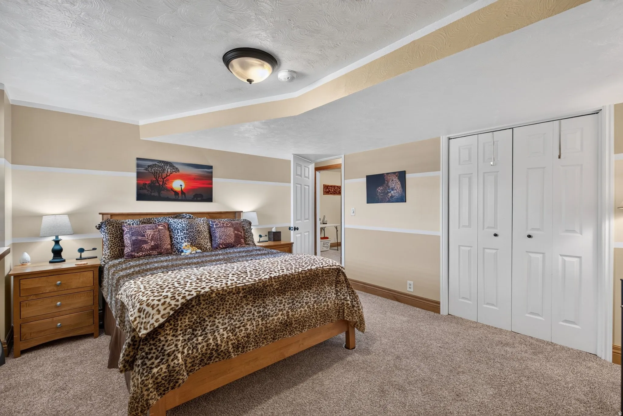 Carpeted room featuring a wood-finish bed frame, two wood-finish nightstands, a ceiling-mounted light fixture, and bifold closet doors