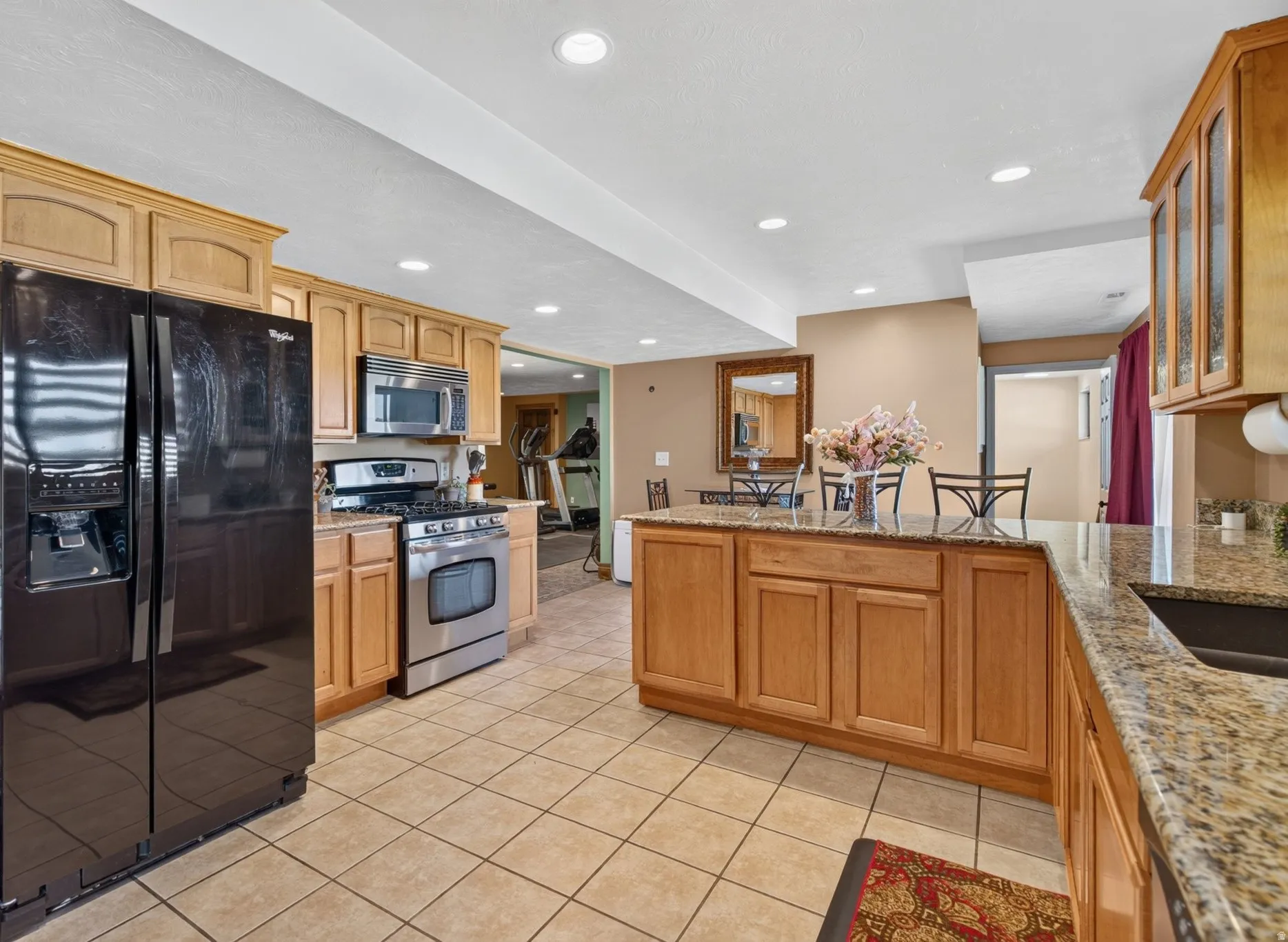 Kitchen featuring light wood cabinetry, granite-finish countertops, stainless steel appliances, and tiled flooring