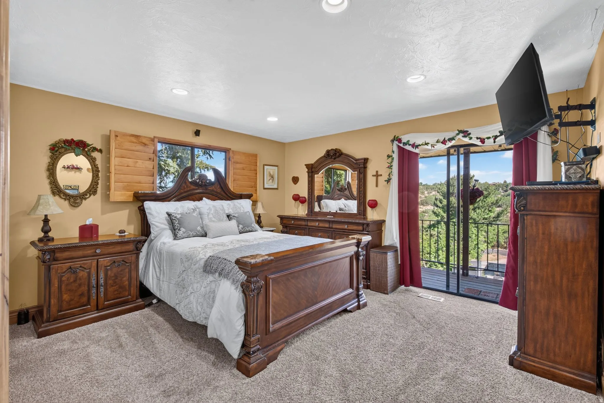 Spacious room featuring carpet flooring, recessed lighting, a window with wood shutters, and a glass-paneled sliding door opening to a private balcony