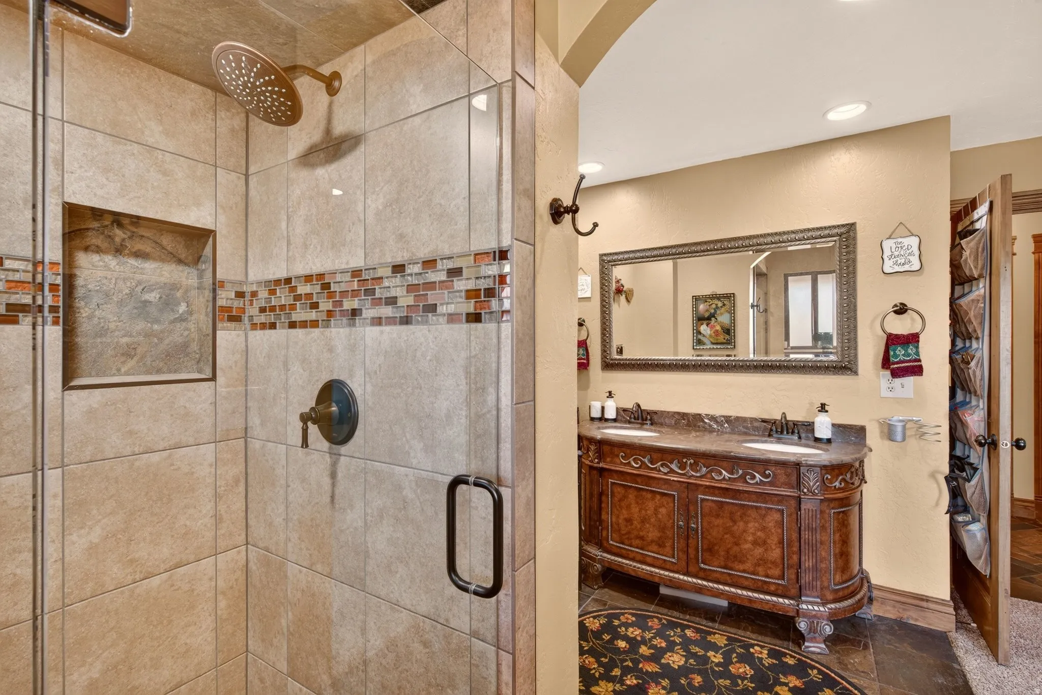 Tiled walk-in shower with a glass enclosure, integrated niche, and an overhead rain showerhead