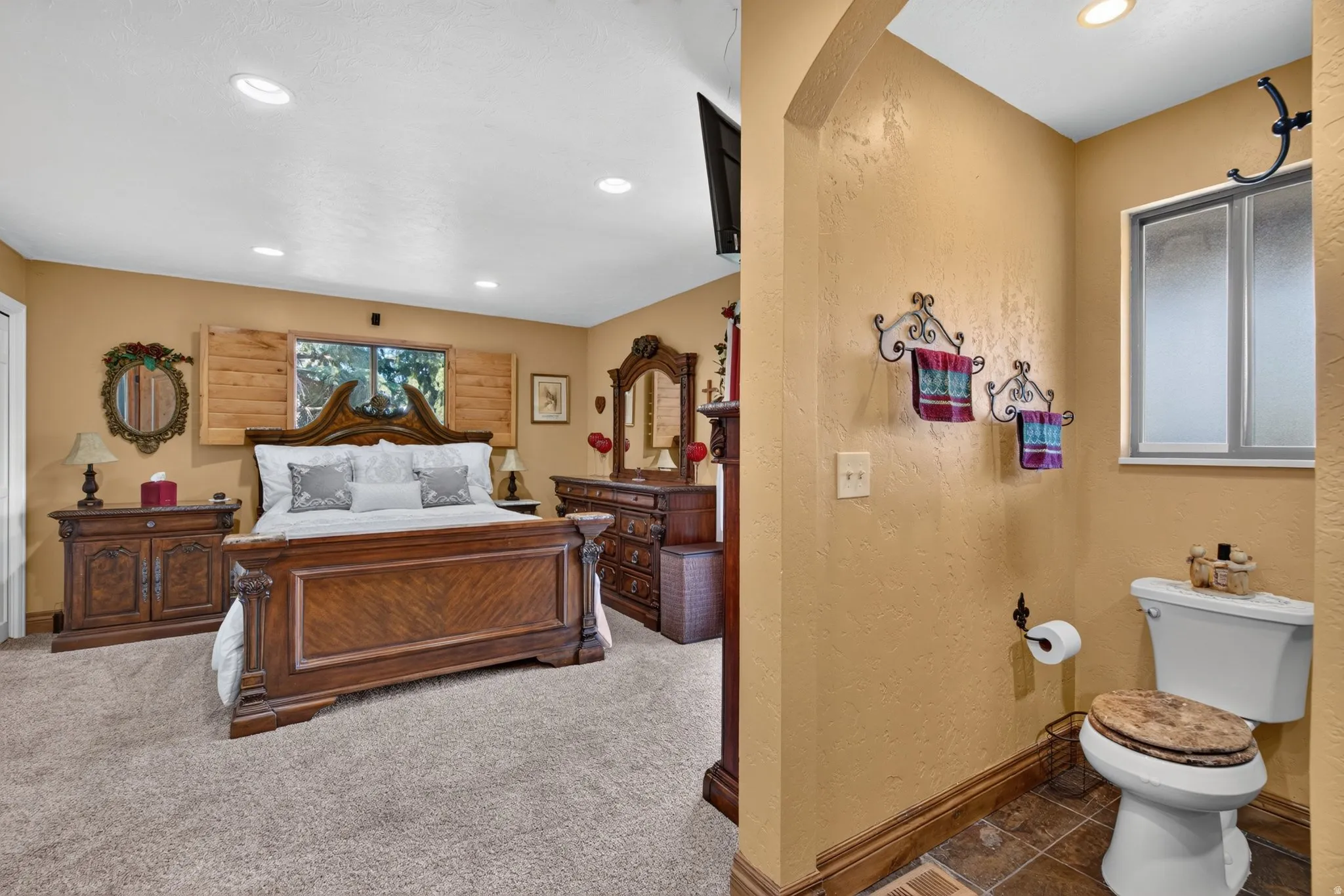 Spacious bedroom featuring recessed lighting, a window with wooden shutters, and plush carpet flooring