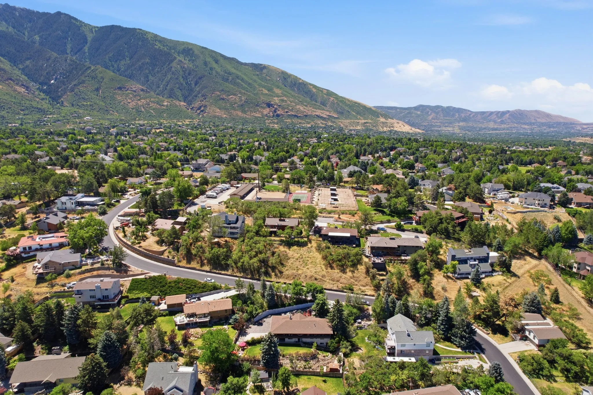 Expansive aerial perspective showcasing a residential community with mature trees and mountain backdrops