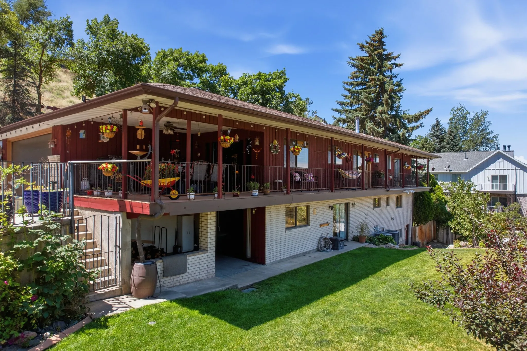 Two-story property with a covered upper-level deck, lower-level patio, and a sloped backyard