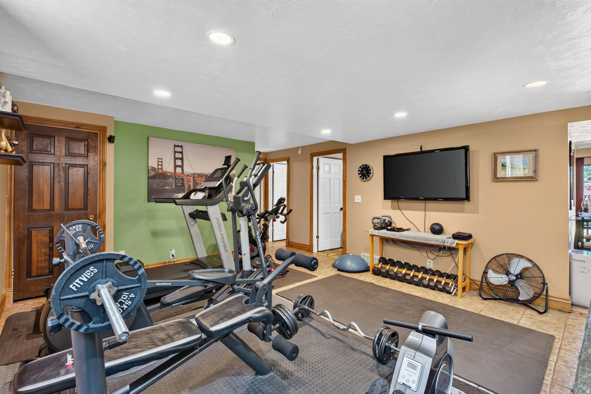 Dedicated fitness area featuring recessed lighting, a mounted television, and tiled flooring