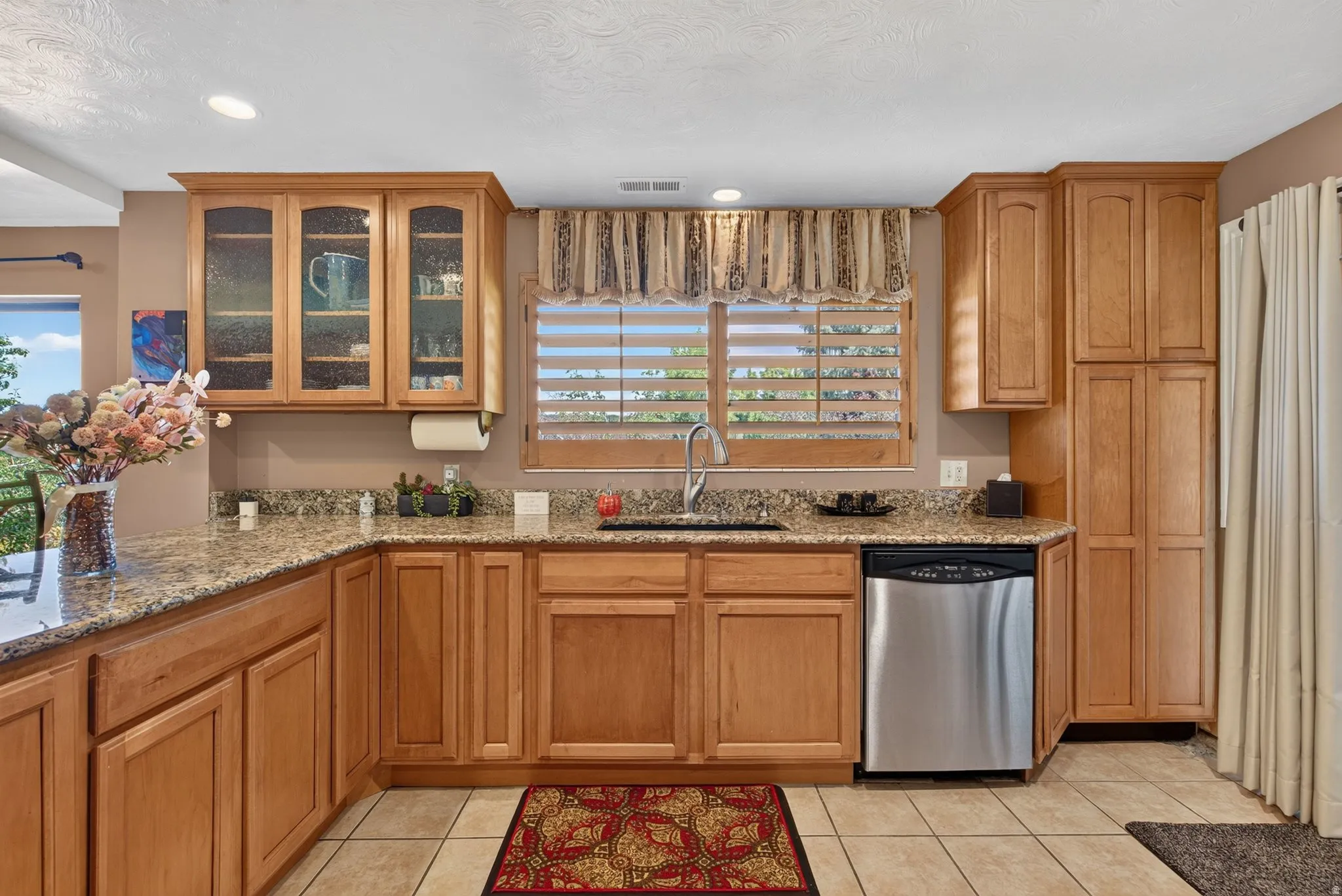 Kitchen featuring wood-finish cabinetry, granite countertops, and tile flooring
