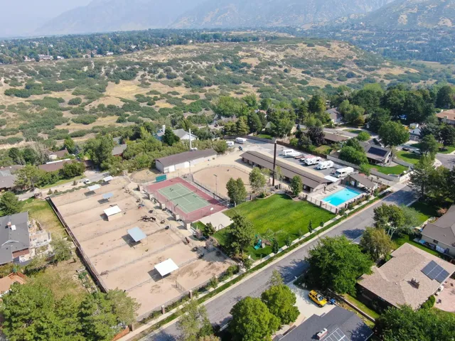 Expansive property featuring multiple equestrian paddocks with shelters, a full-size tennis court, a swimming pool with surrounding deck, and a manicured lawn area