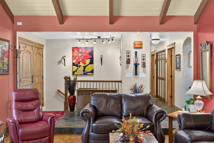 Living space featuring a coffered ceiling with exposed beams, an open doorway, and hardwood flooring