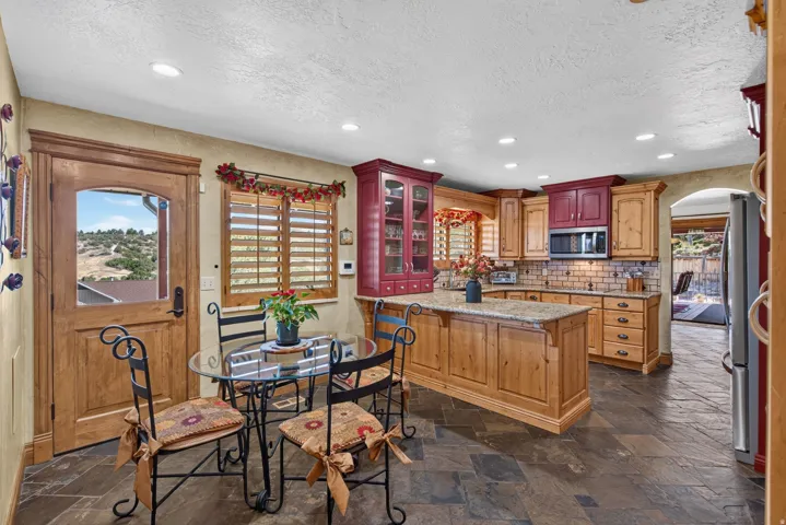 Kitchen featuring slate floor tiles, a center island with a light-toned countertop, and wood cabinetry with varied finishes