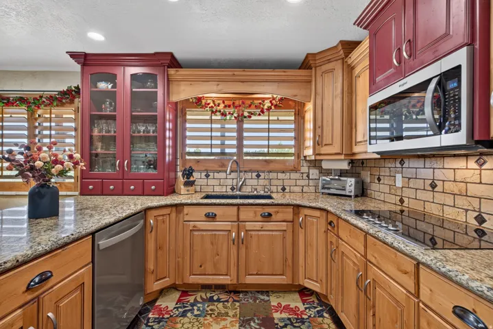 U-shaped kitchen featuring granite countertops, wood-finish cabinetry, a tile backsplash with diamond accents, a built-in microwave, and a black cooktop