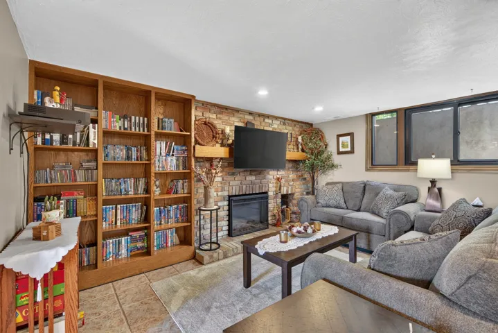 Living area featuring a brick-faced fireplace with hearth, a wood mantel, and built-in shelving