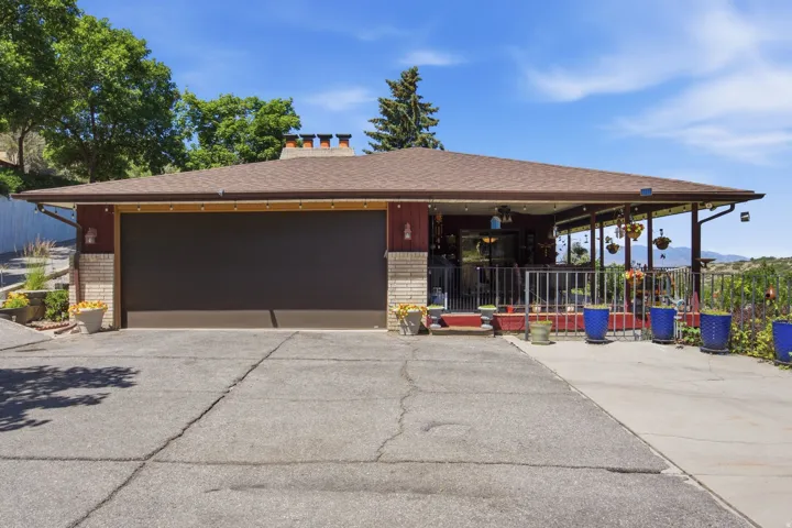 Exterior featuring a two-car garage with an overhead door, brick accents, and a covered porch