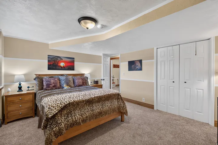 Carpeted room featuring a wood-finish bed frame, two wood-finish nightstands, a ceiling-mounted light fixture, and bifold closet doors