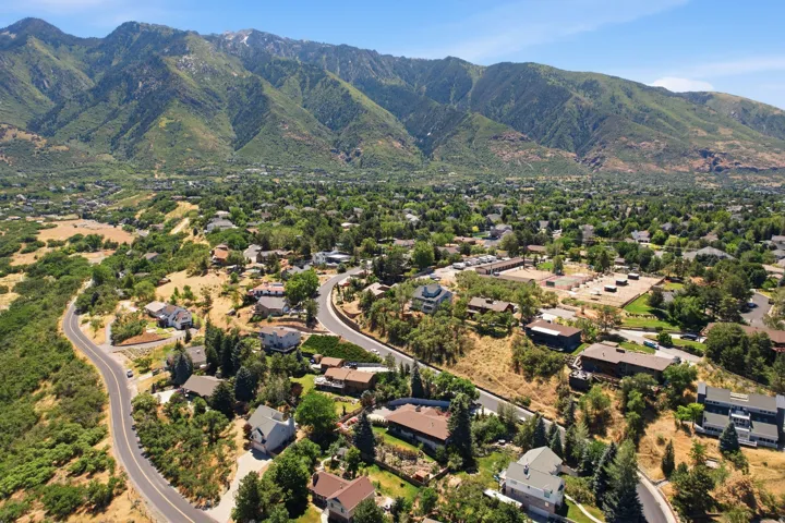 Expansive mountain backdrop with a residential area featuring numerous homes, mature trees, and paved roadways