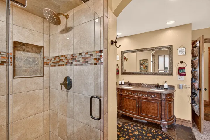 Tiled walk-in shower with a glass enclosure, integrated niche, and an overhead rain showerhead