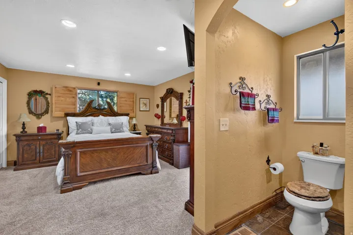 Spacious bedroom featuring recessed lighting, a window with wooden shutters, and plush carpet flooring