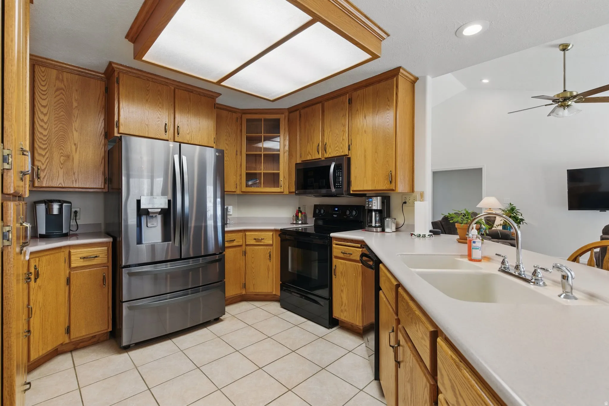 Kitchen featuring abundant wood cabinetry, an integrated stainless steel refrigerator, black range, and dual-basin sink