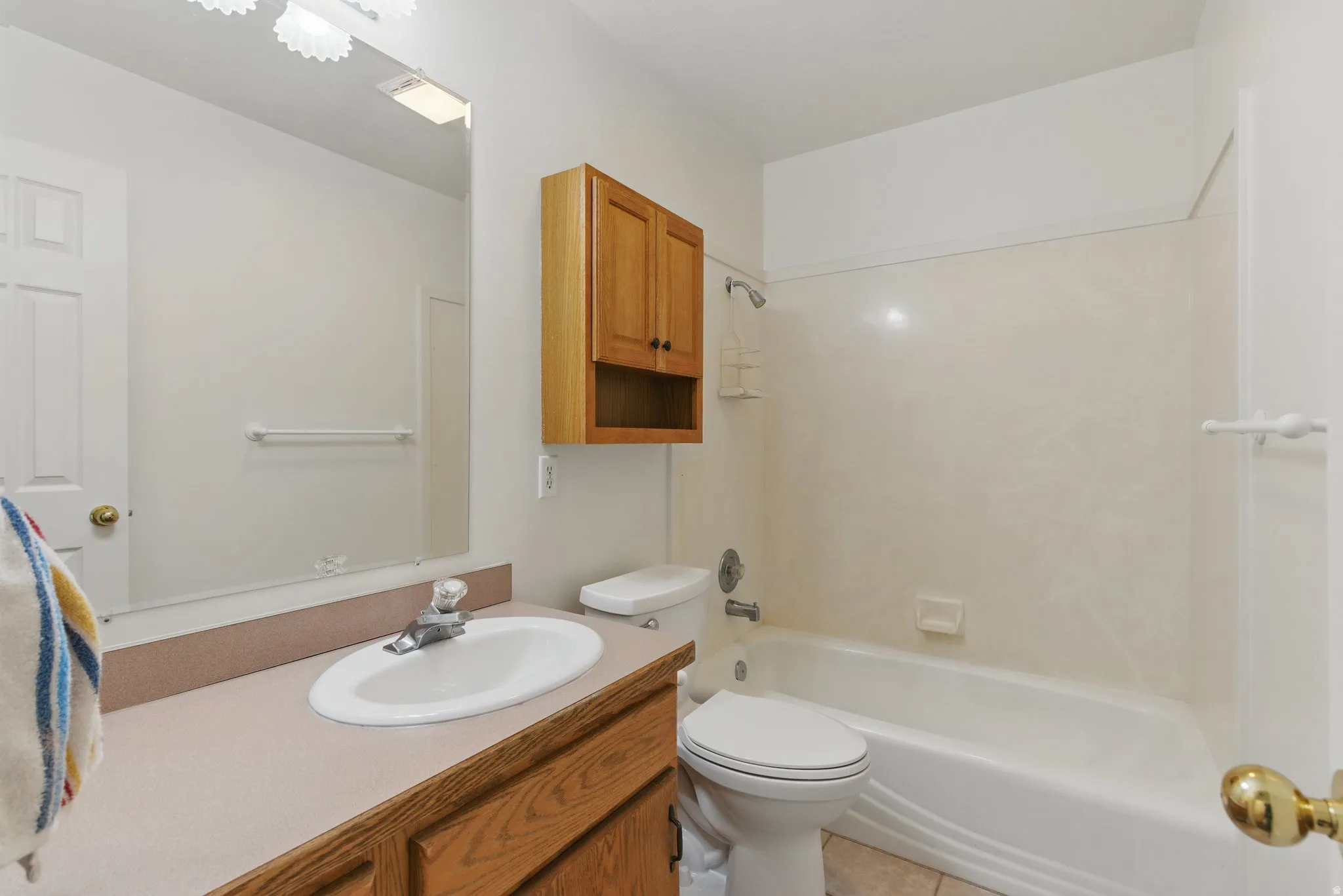 Bathroom featuring a vanity with an integrated sink, a rectangular mirror, and a full-size bathtub with shower