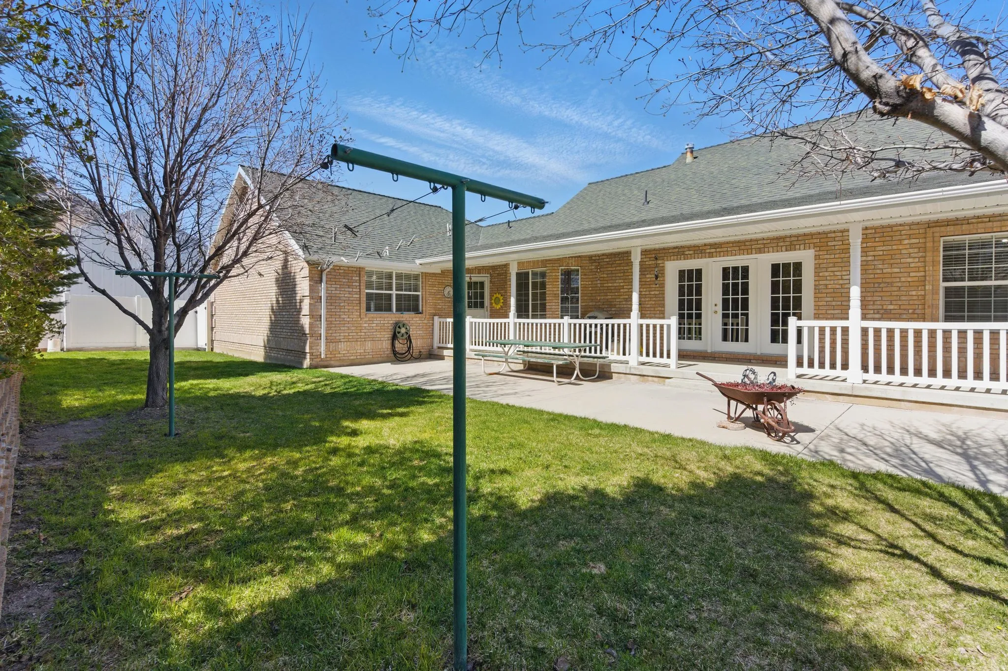 Expansive patio area featuring brick siding, white railing, and double French doors