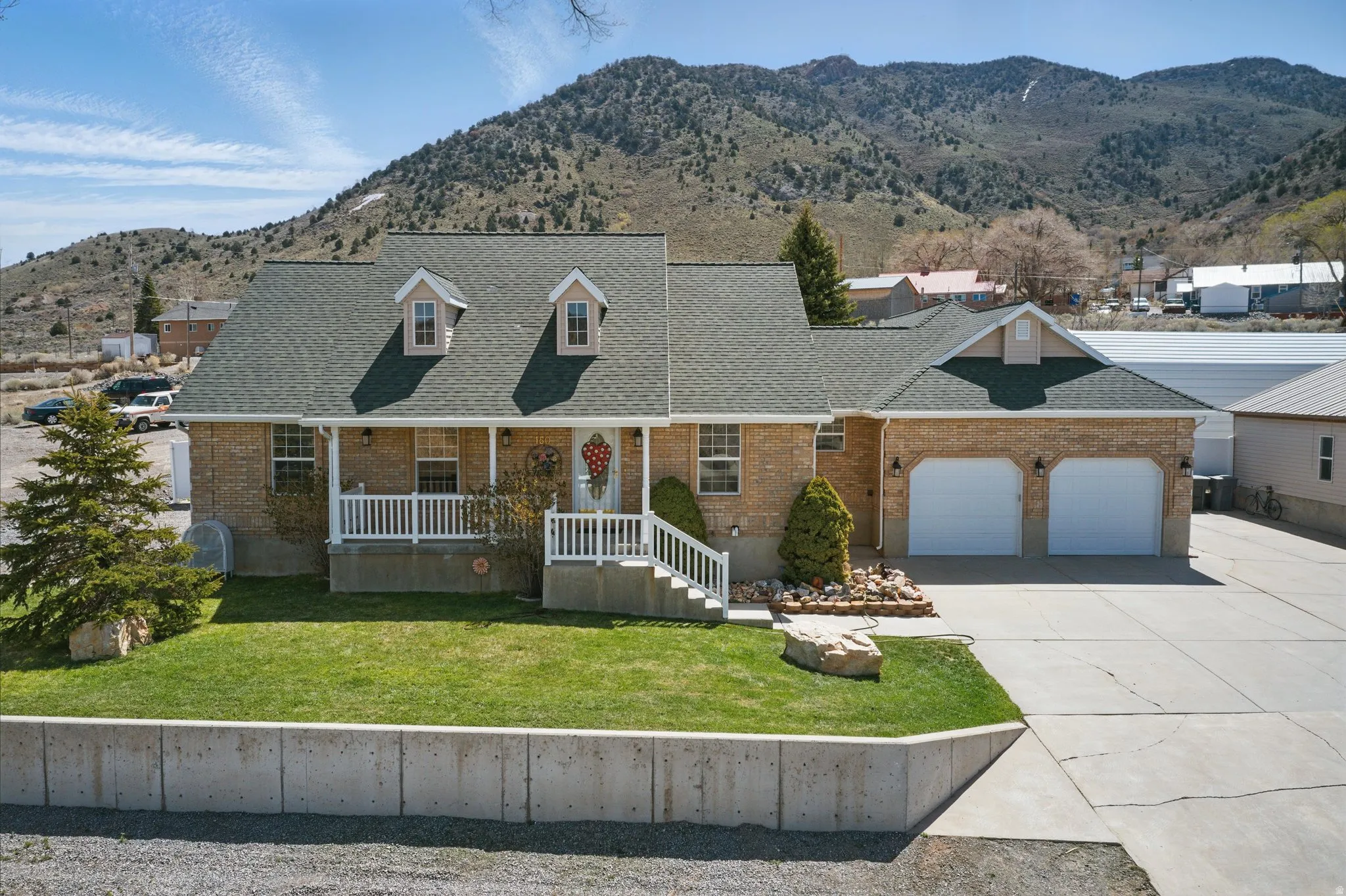 Brick exterior with a covered front porch, two dormer windows, and a two-car garage