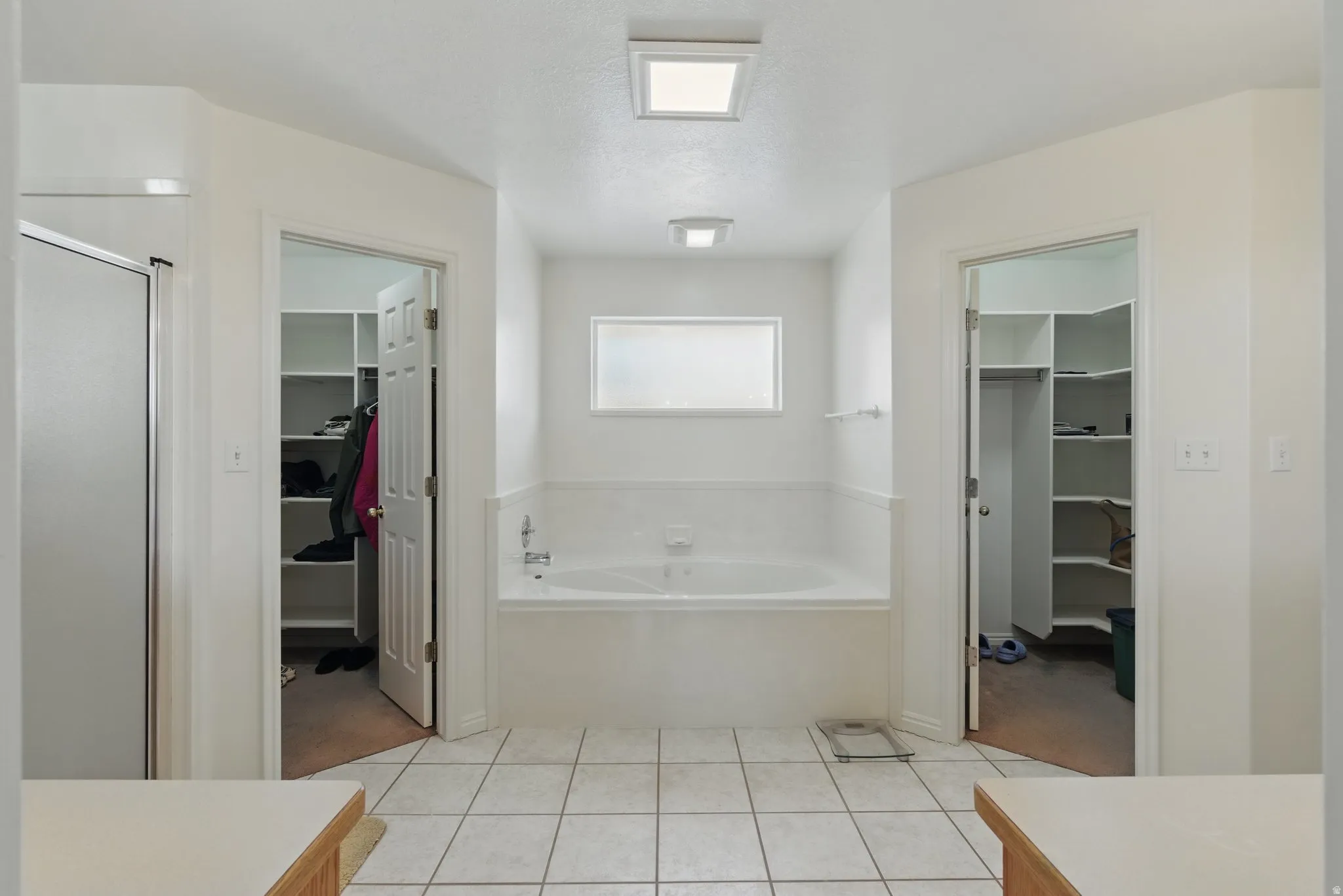 Soaking tub and two walk-in closets with built-in shelving, complemented by a separate shower enclosure