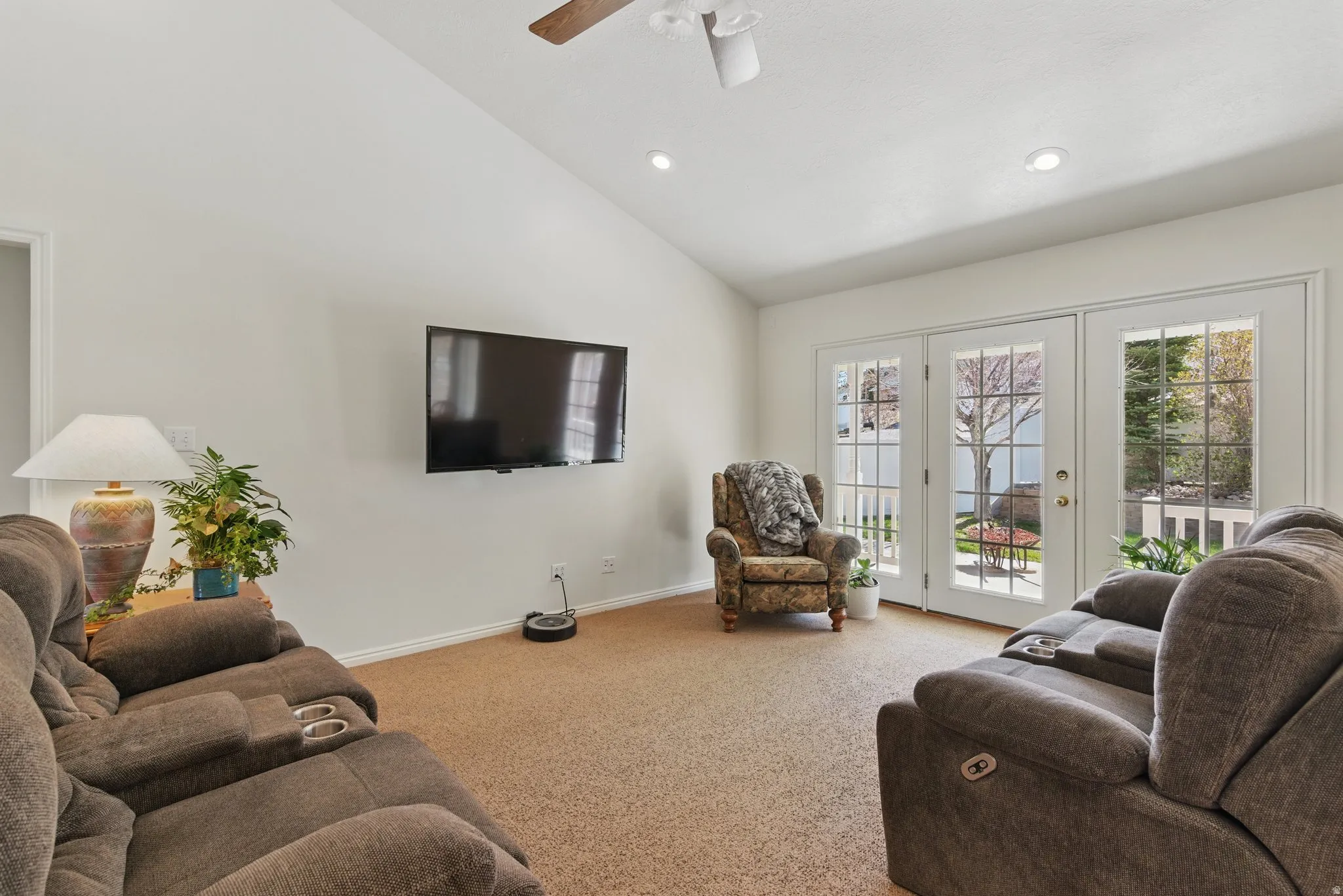 Vaulted ceilings enhance this living area featuring neutral carpet flooring and white walls