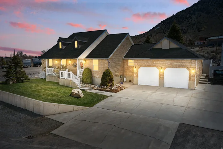 Brick exterior residence featuring a two-car garage, concrete driveway, and a front porch with white railings