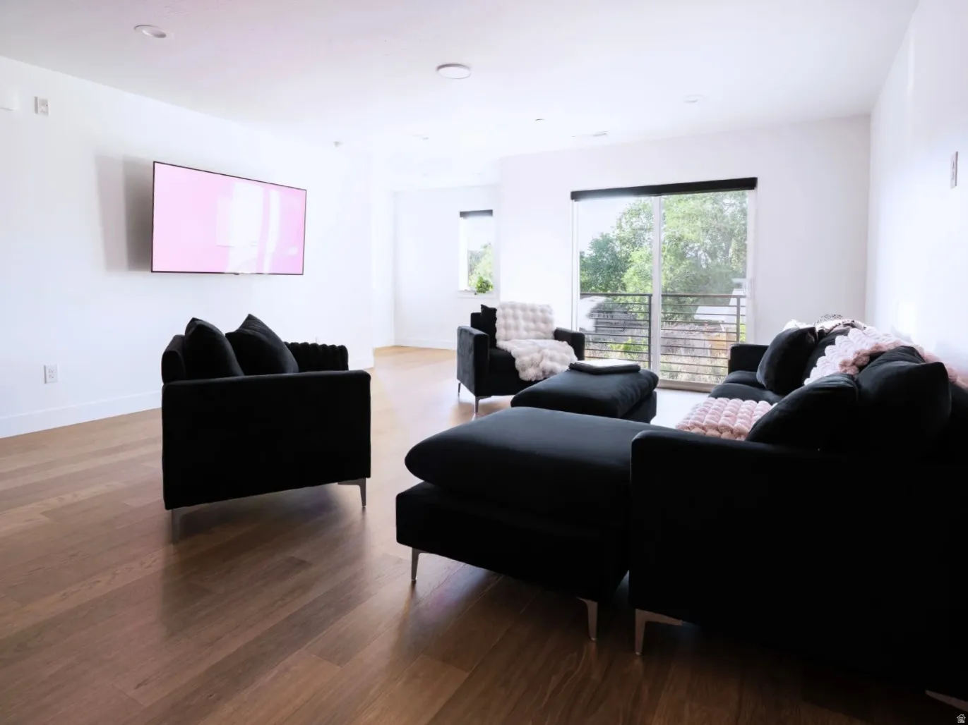 Spacious living area featuring wood-finish flooring, recessed lighting, and a wall-mounted flat-screen television