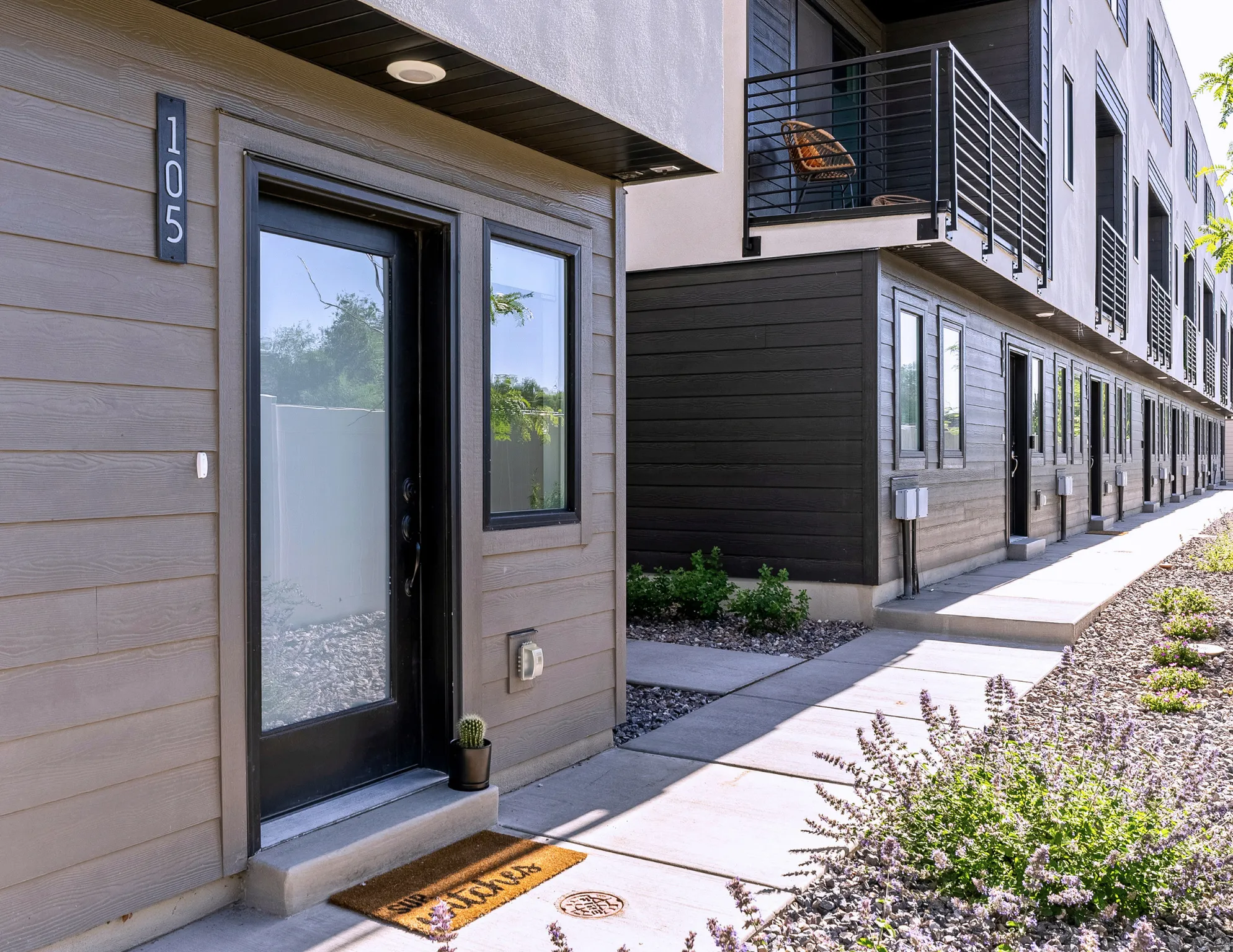 Modern exterior with horizontal siding, a glass-paneled entry door, and dark-framed windows