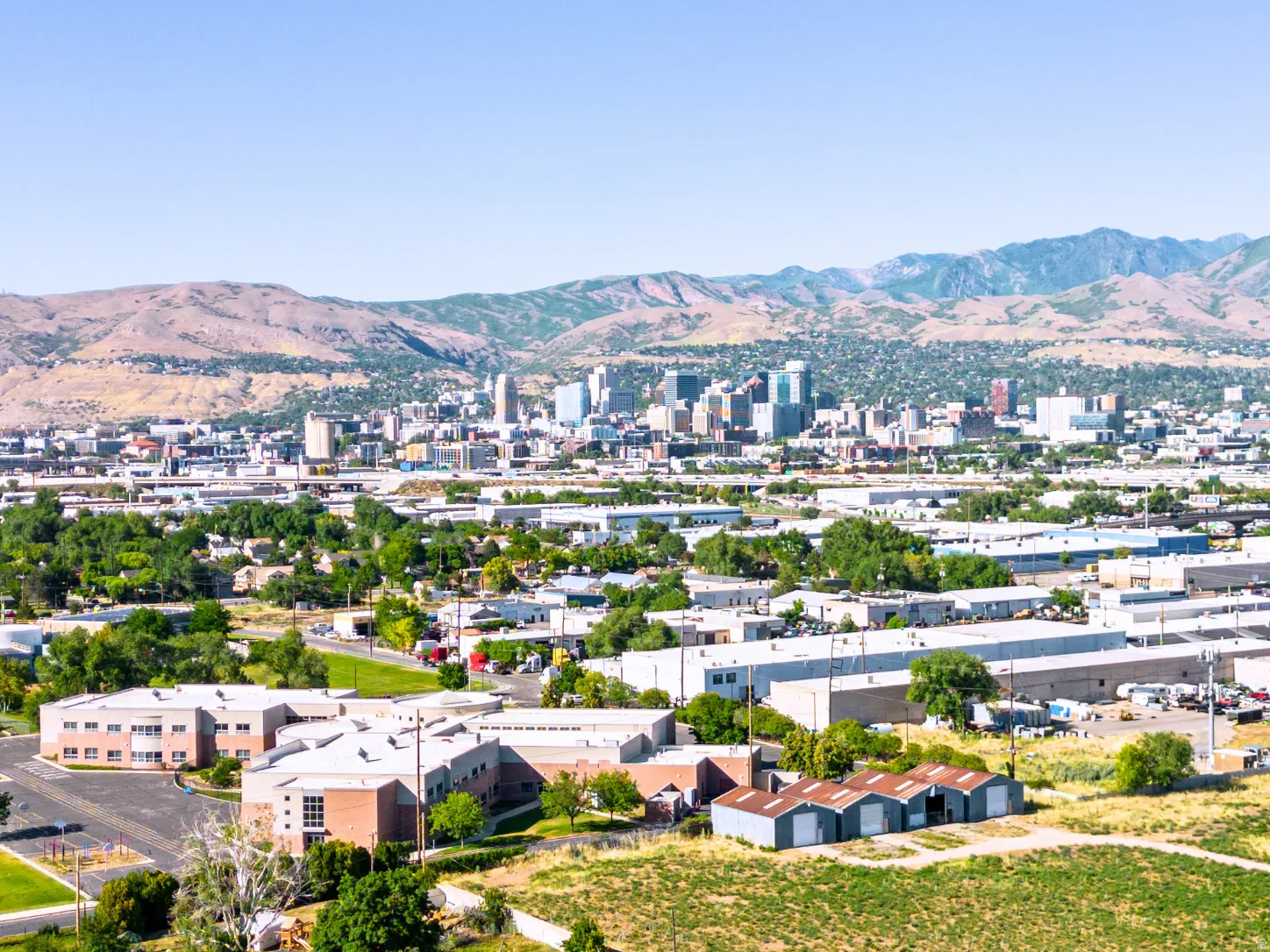 Expansive urban landscape featuring a distant city skyline with prominent buildings, complemented by a mountainous backdrop