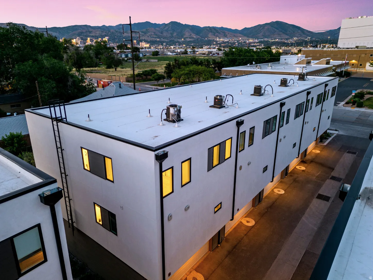 Contemporary multi-unit structure featuring a white facade, black-framed windows, and flat roofline