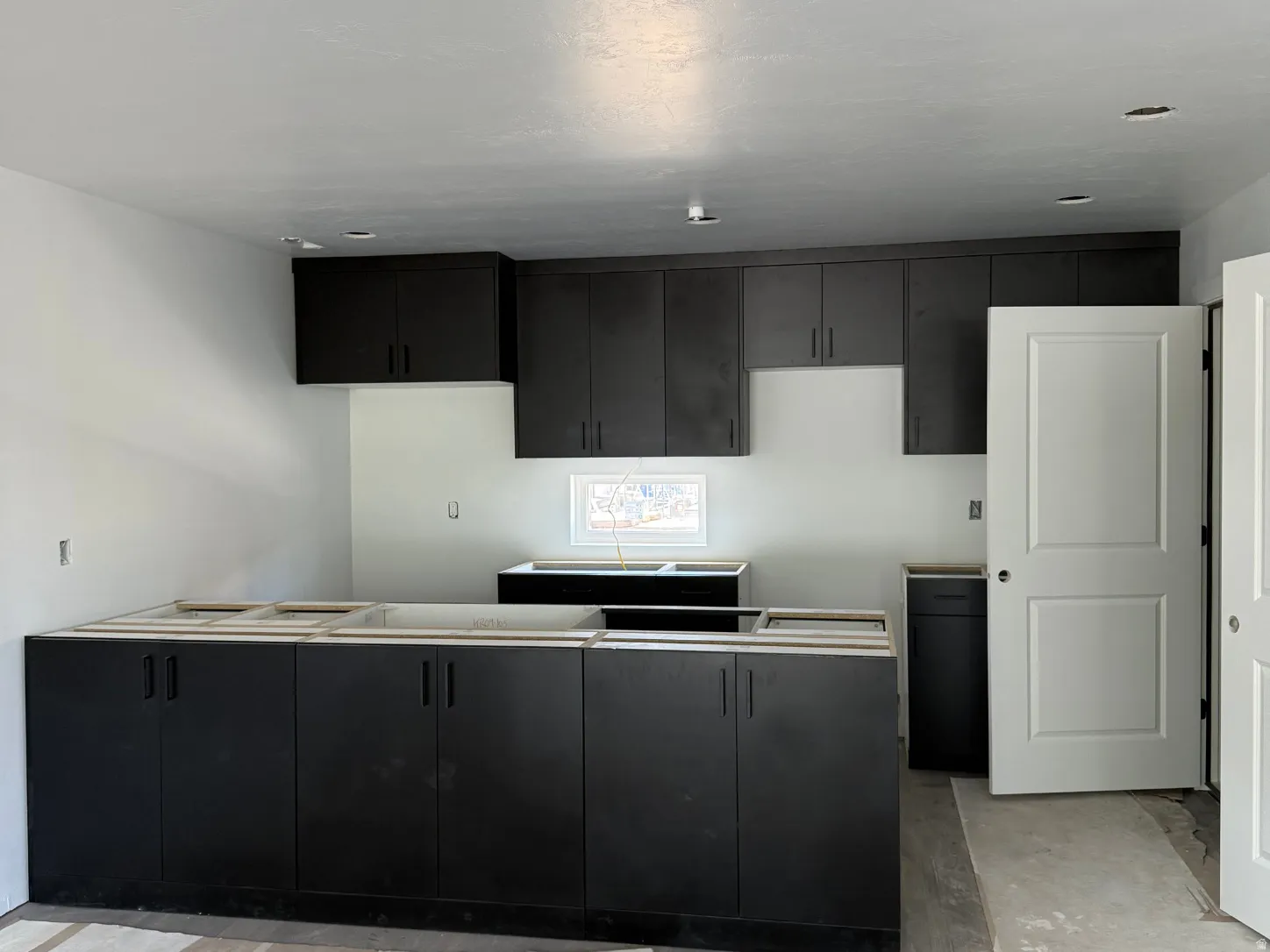 Kitchen featuring dark-toned cabinetry, recessed lighting, and a white interior door