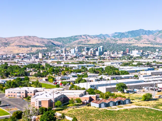 Expansive urban landscape featuring a distant city skyline with prominent buildings, complemented by a mountainous backdrop