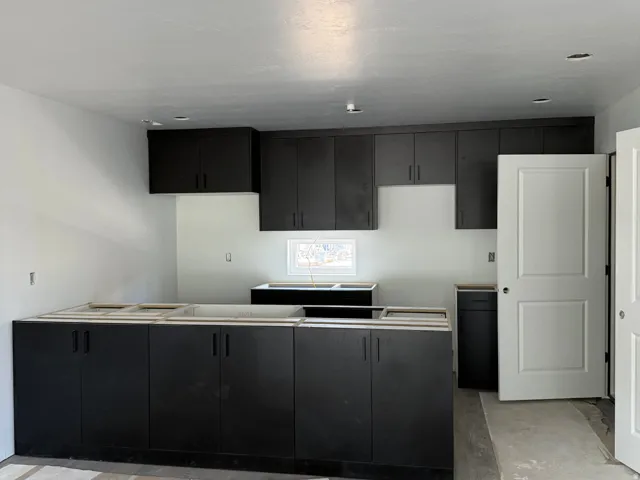 Kitchen featuring dark-toned cabinetry, recessed lighting, and a white interior door