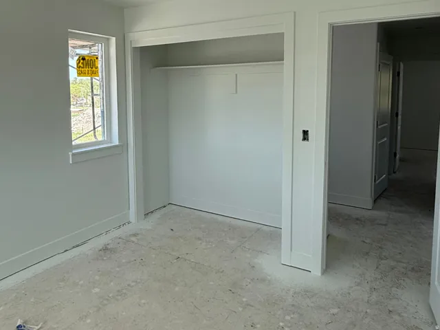 Room featuring a single-pane window, white trim, and a built-in closet with a single shelf and hanging rod