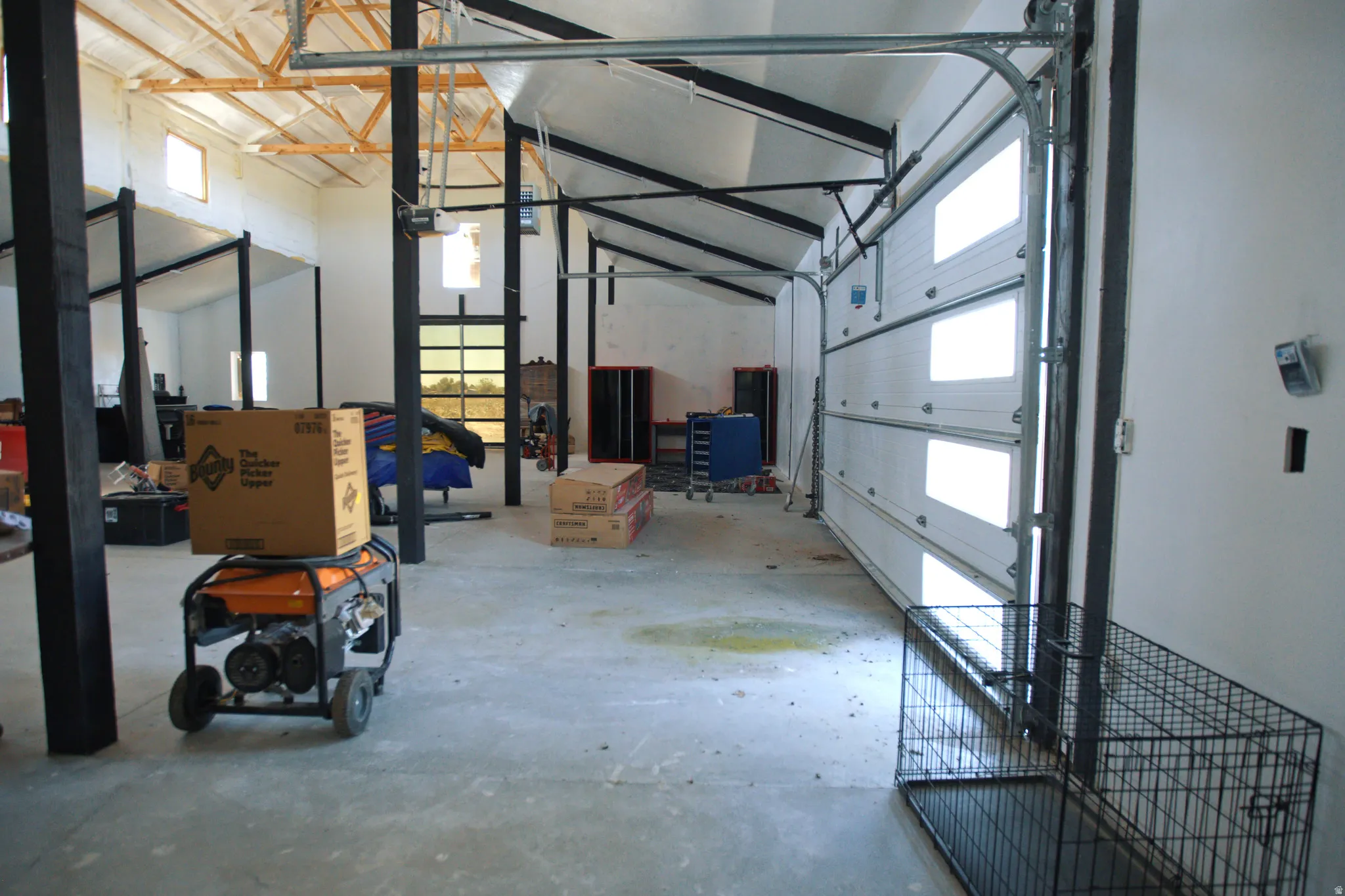Spacious interior with exposed ceiling trusses and an overhead garage door featuring integrated translucent panels