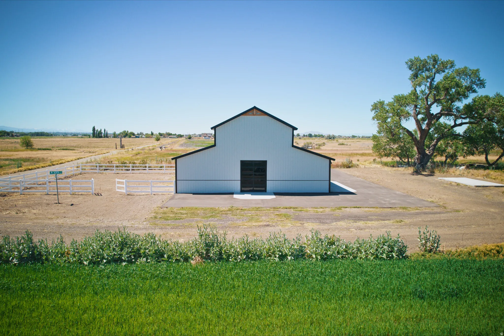 White barn structure featuring a black roof, black trim, and large black doors