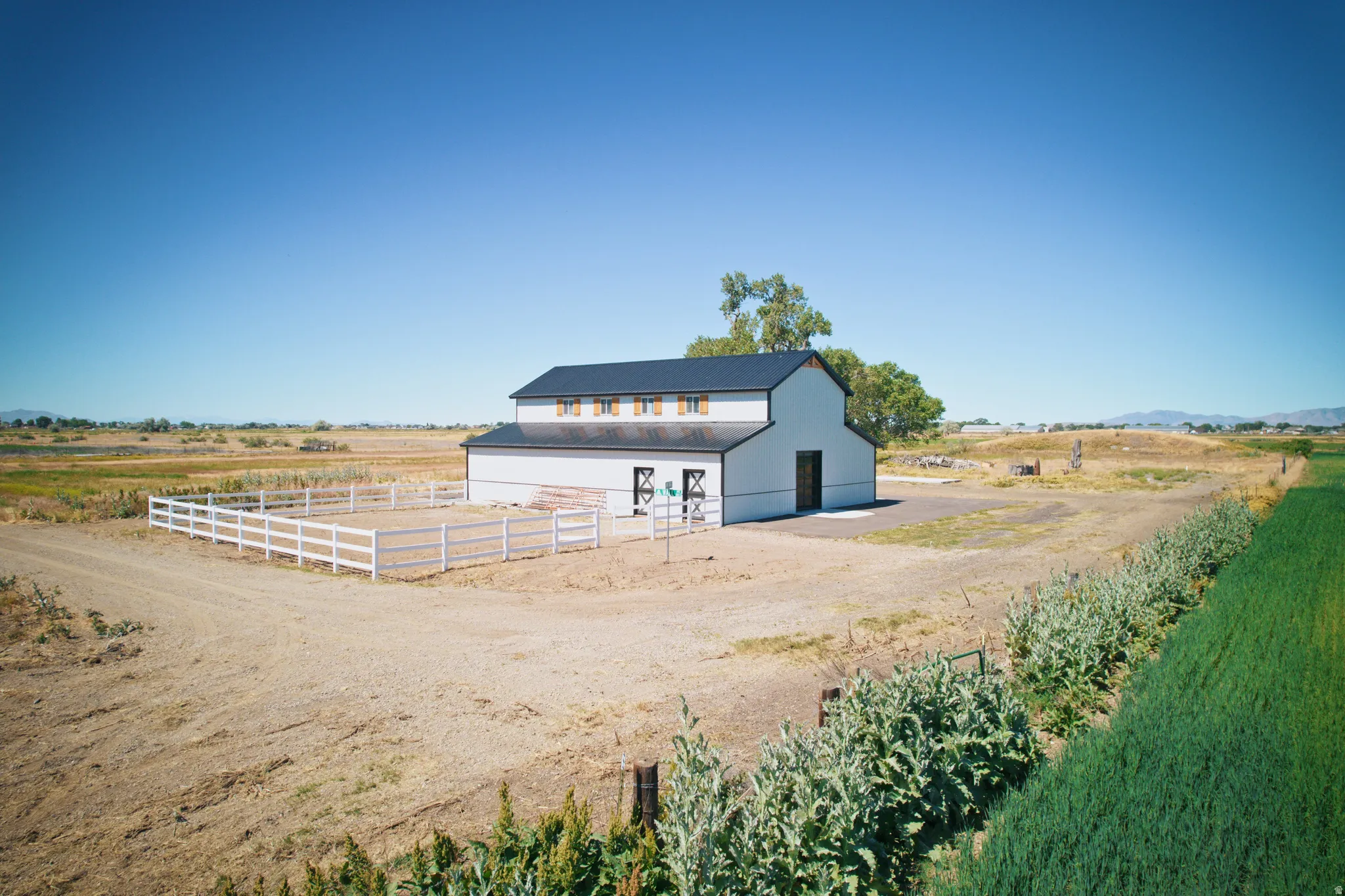 White two-story barn structure with a dark roof