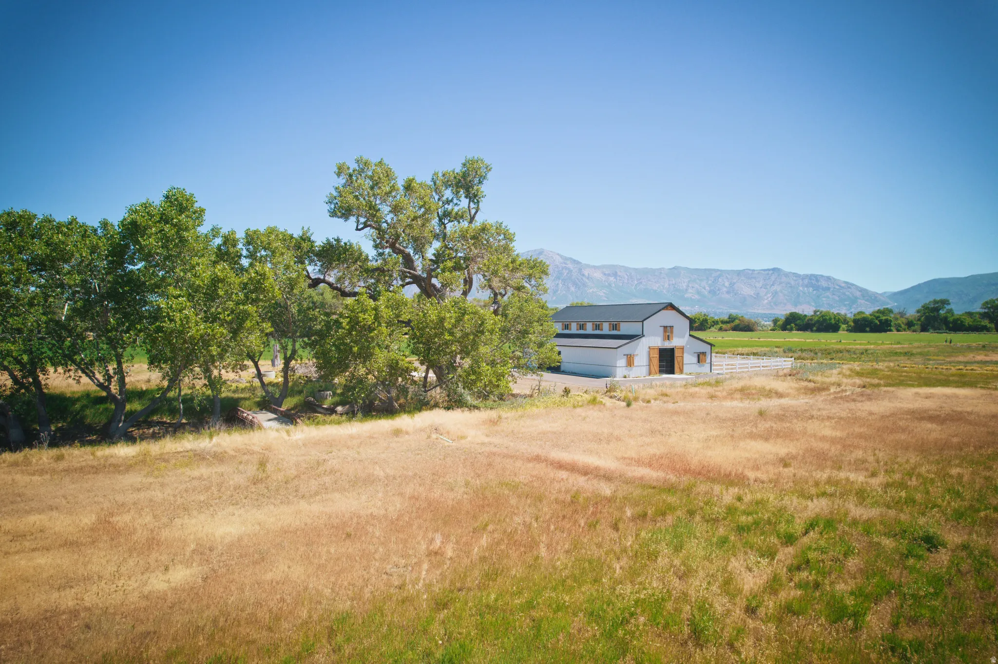 Modern white barn-style structure featuring a dark roof, exposed wood doors, and clear-story windows