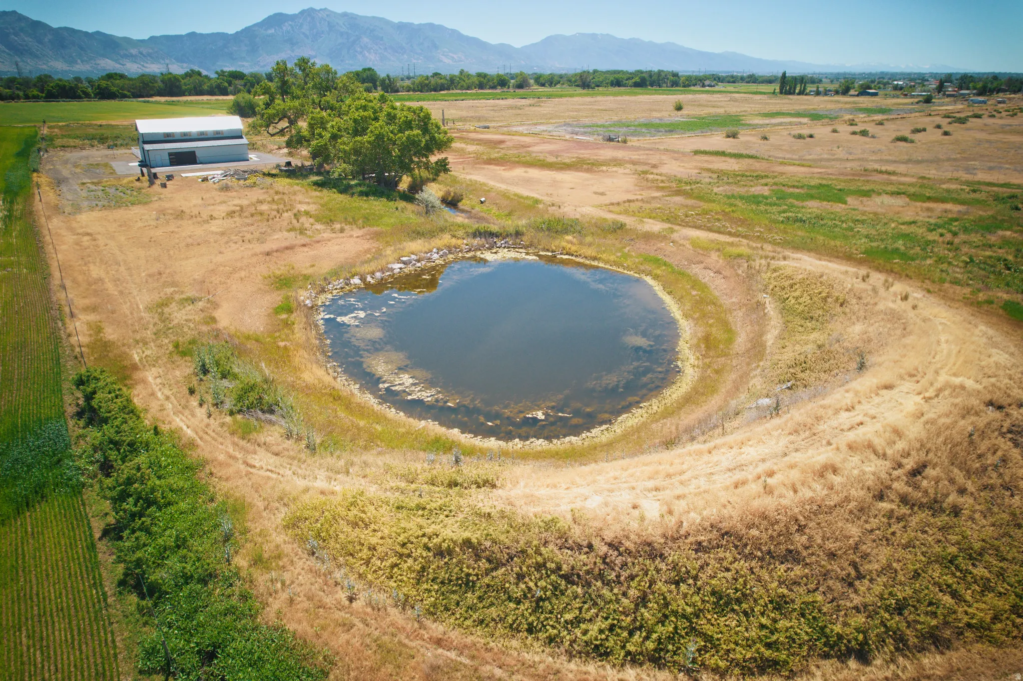Expansive acreage featuring a private pond, large detached barn, mature trees, and mountainous backdrop